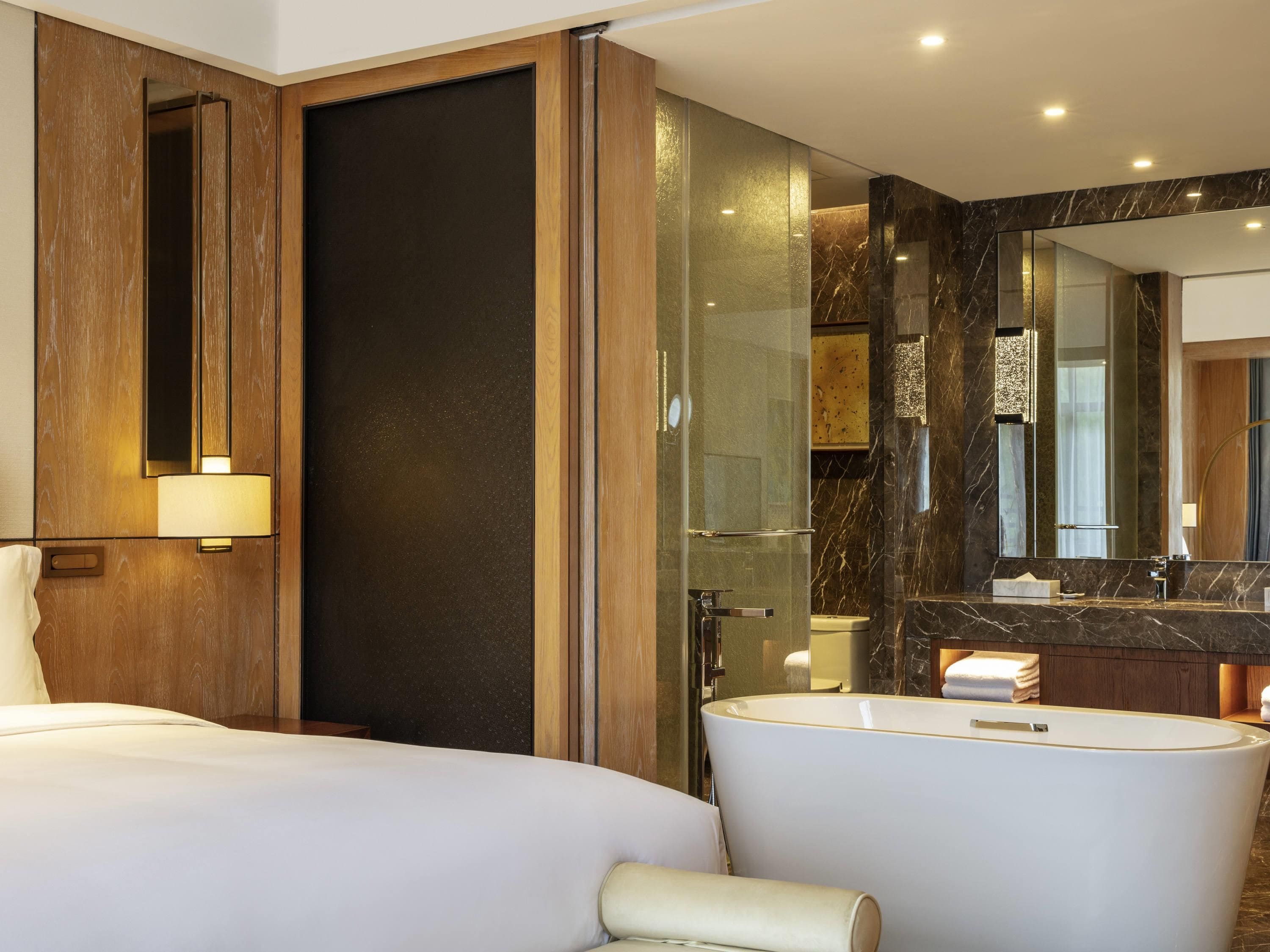 A modern bathroom with a bathtub, a large mirror, and a wooden door.