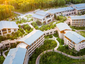 A modern building complex with multiple connected structures, green spaces, and a central courtyard.