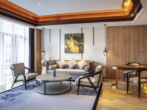 A modern living room with a sofa, chairs, a round coffee table, and a dining table.