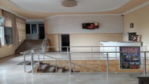 A lobby with a staircase, a reception desk, and a television screen.