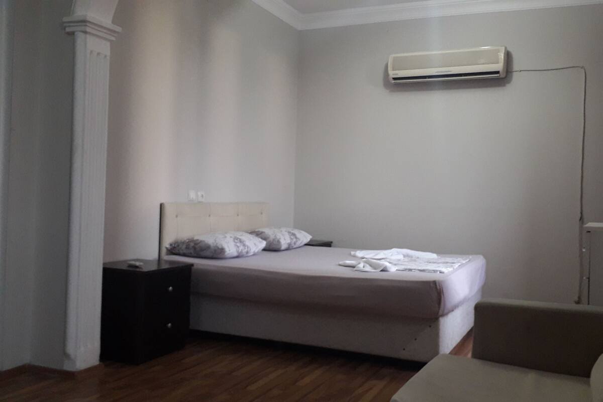 Une chambre à coucher comprenant un lit, une table de chevet, un climatiseur et une chaise.