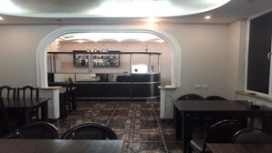A dining area with a kitchen in the background, featuring a counter and shelves with items.