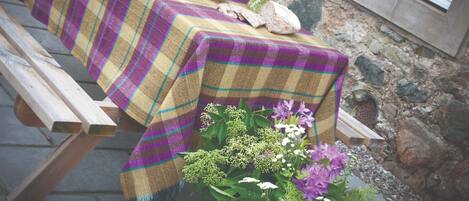 A table set with a plaid tablecloth, a bowl of oranges, a vase of tulips, and a bouquet of flowers.