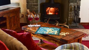 A cozy living room with a wooden table, a Scrabble game, and two glasses of red wine. - Leny Estate (Callander)