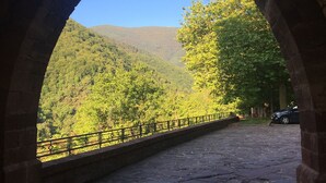 Une structure en pierre en forme d’arche, d’où l’on peut admirer une colline boisée.