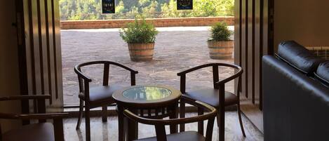 Eine offene Tür führt auf eine Terrasse mit einem Tisch, Stühlen, einer Couch und Topfpflanzen.