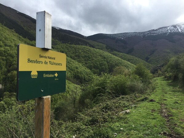 A sign indicating 'Sendero Natural Sendero de Valvanera' with an arrow pointing right and 'Embalse' below it.