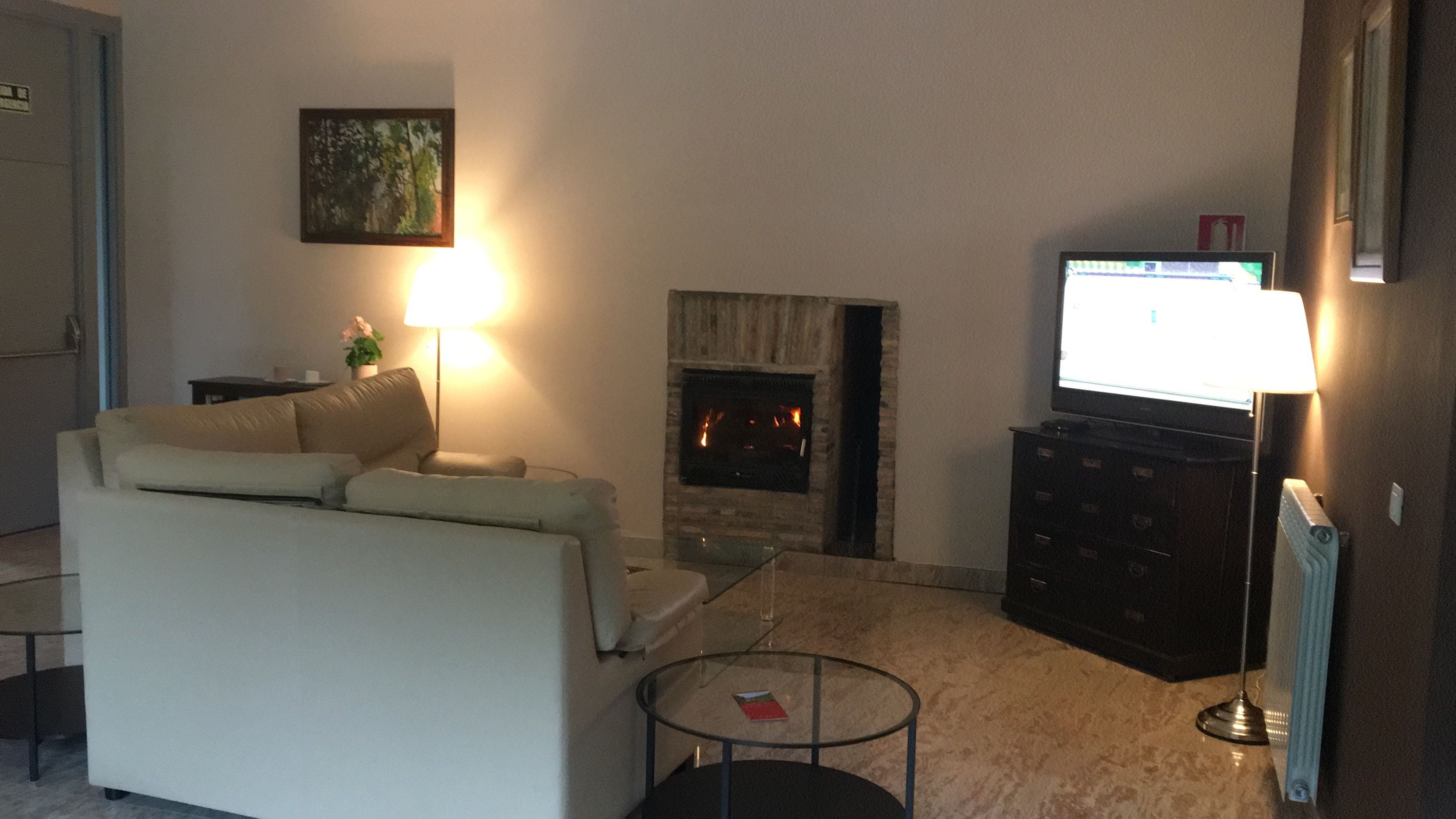 Una sala de estar con chimenea, sofá, televisión y lámpara.