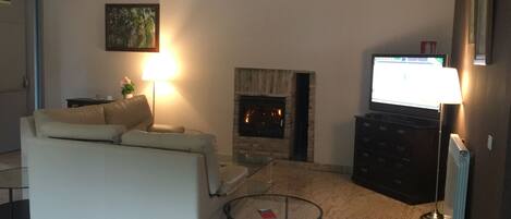 A living room with a fireplace, a sofa, a television, and a lamp.