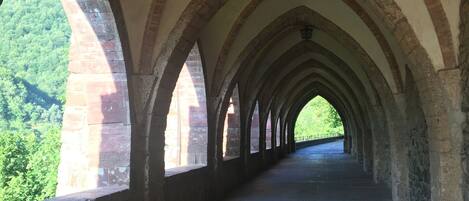 A corridor with a series of arches and a view of greenery outside.