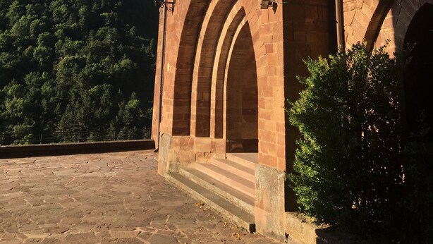 Un bâtiment historique doté de fenêtres en arc de cercle et d’un grand emblème circulaire sur la façade.