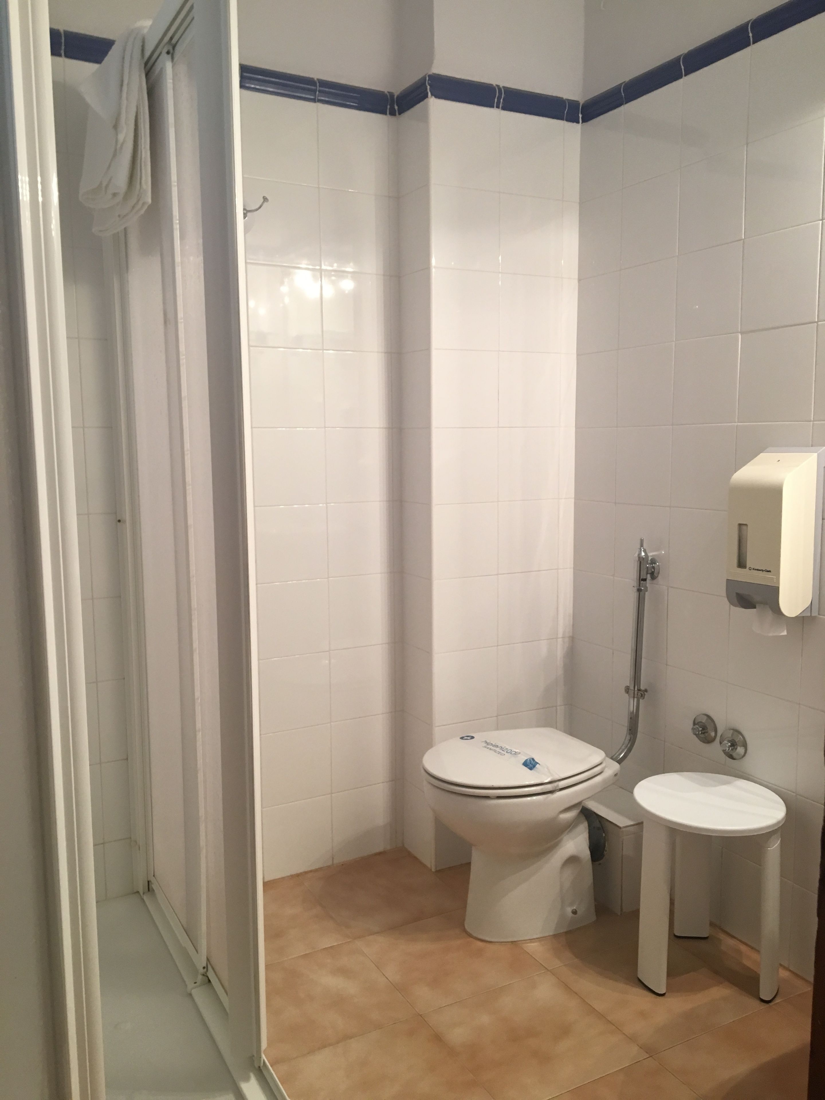 Ett badrum med vita kakelbeklädda väggar, en duschkabin, en toalett och en bidé.
