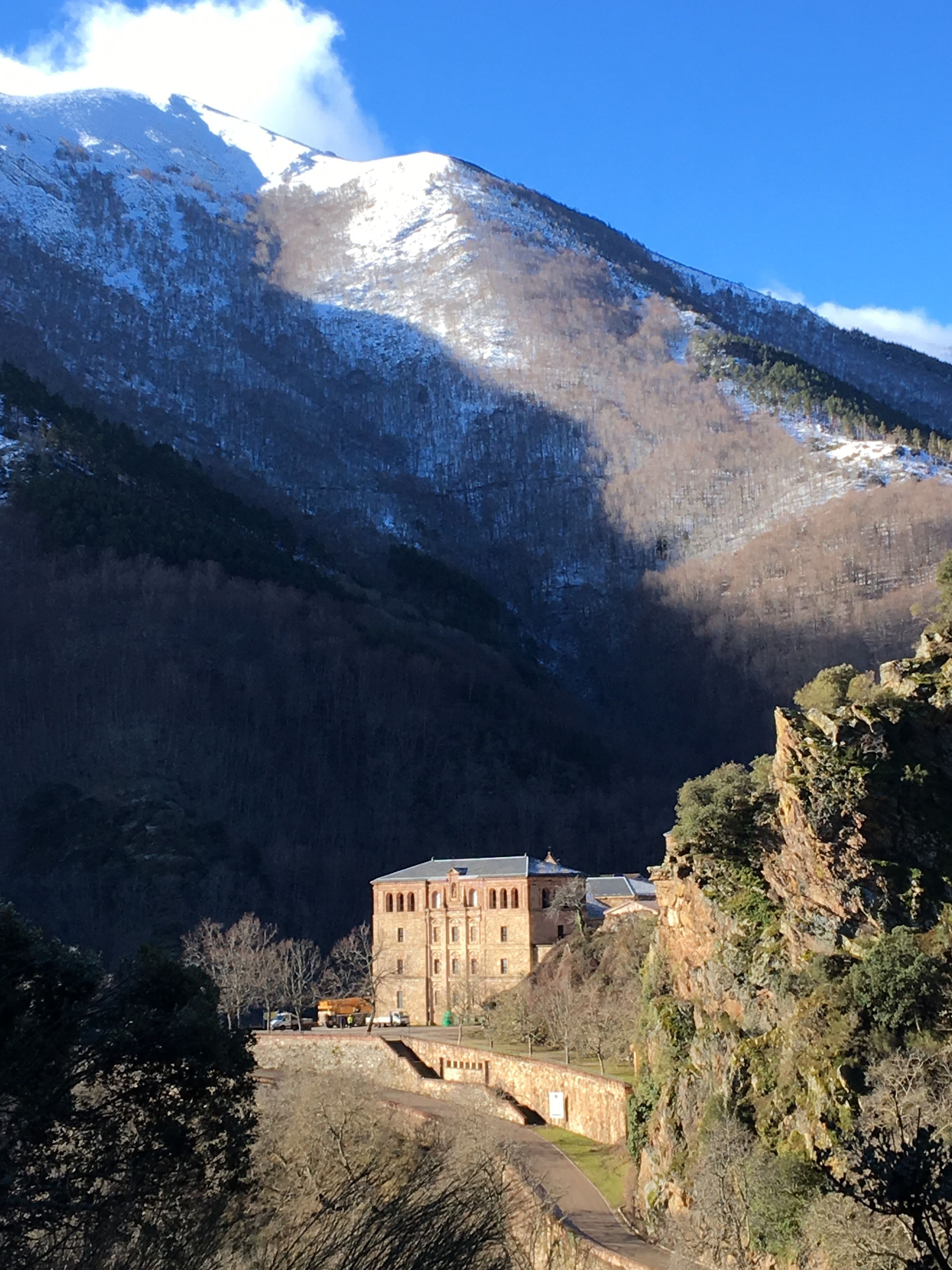 A building with a stone facade, situated at the base of a snow-capped mountain.