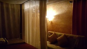 A dimly lit room with a sofa, a lamp, and a curtain. - Baan Aunjai Homestay (Mae Lao)