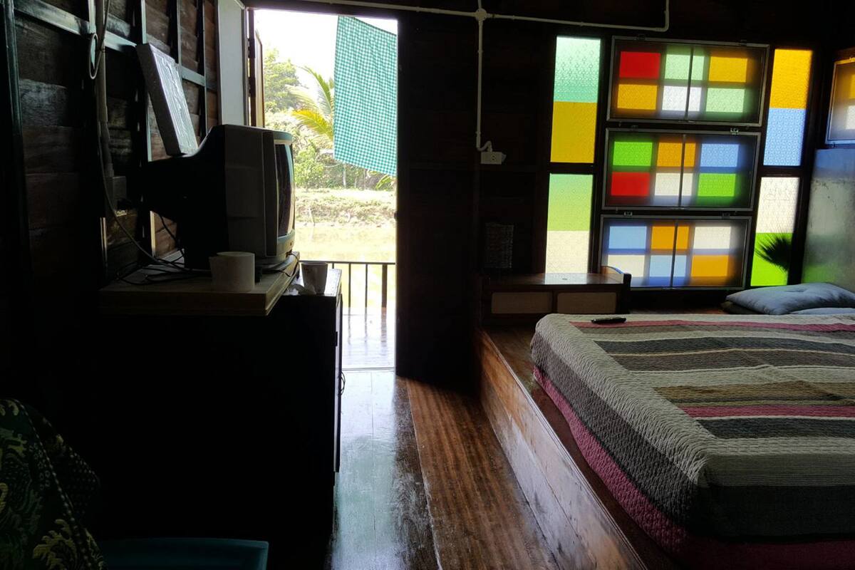 Une chambre avec un lit, une télévision et une fenêtre aux vitraux colorés.