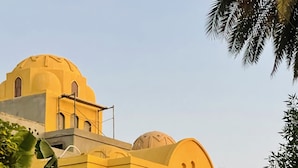 A building with yellow walls and domed roofs, featuring arched windows and a decorative facade. - Jewel Howard Carter Hotel (Luxor)