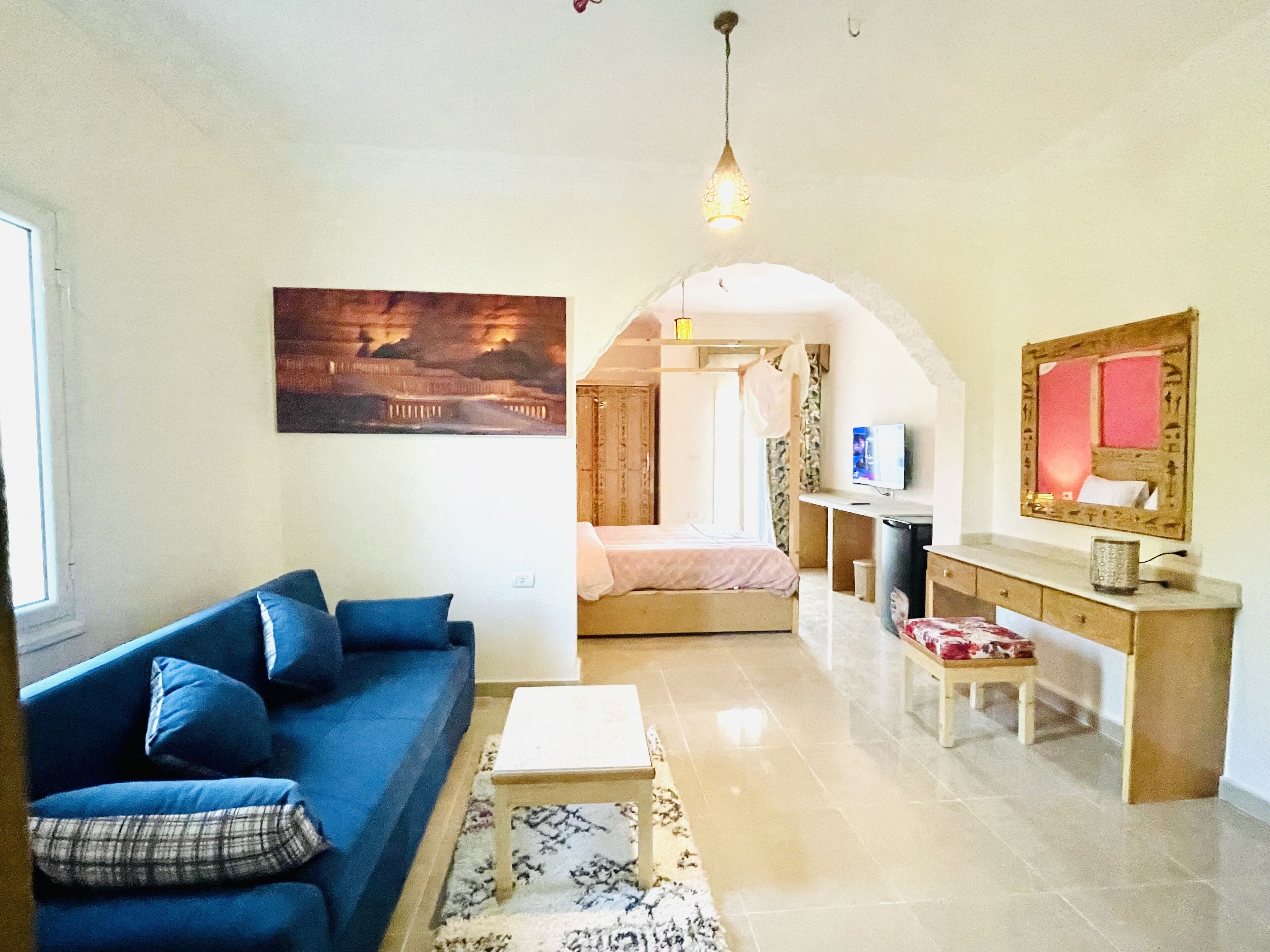 Una sala de estar con un sofá azul, una mesa de centro y un cuadro en la pared.