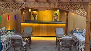 A reception area with a wooden archway, a reception desk, and wicker furniture. - Jewel Howard Carter Hotel (Luxor)
