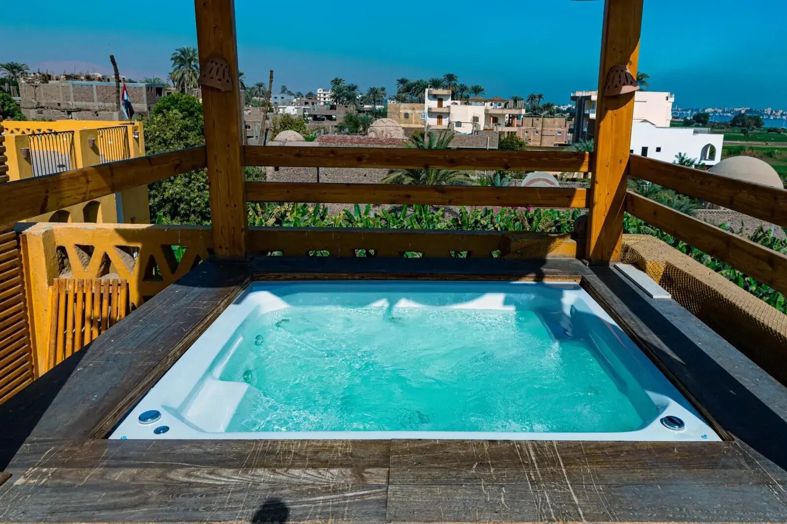 Eine Holzterrasse mit Whirlpool mit Blick auf eine Küstenstadt.