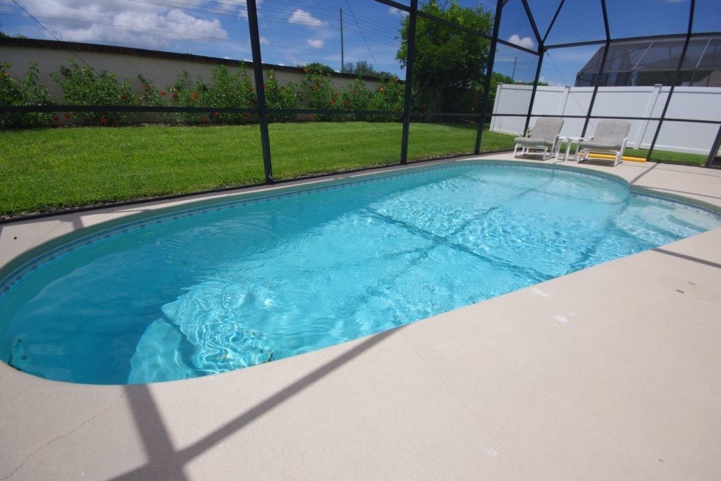 Une piscine rectangulaire à l’eau d’un bleu limpide, entourée d’une terrasse de couleur beige.