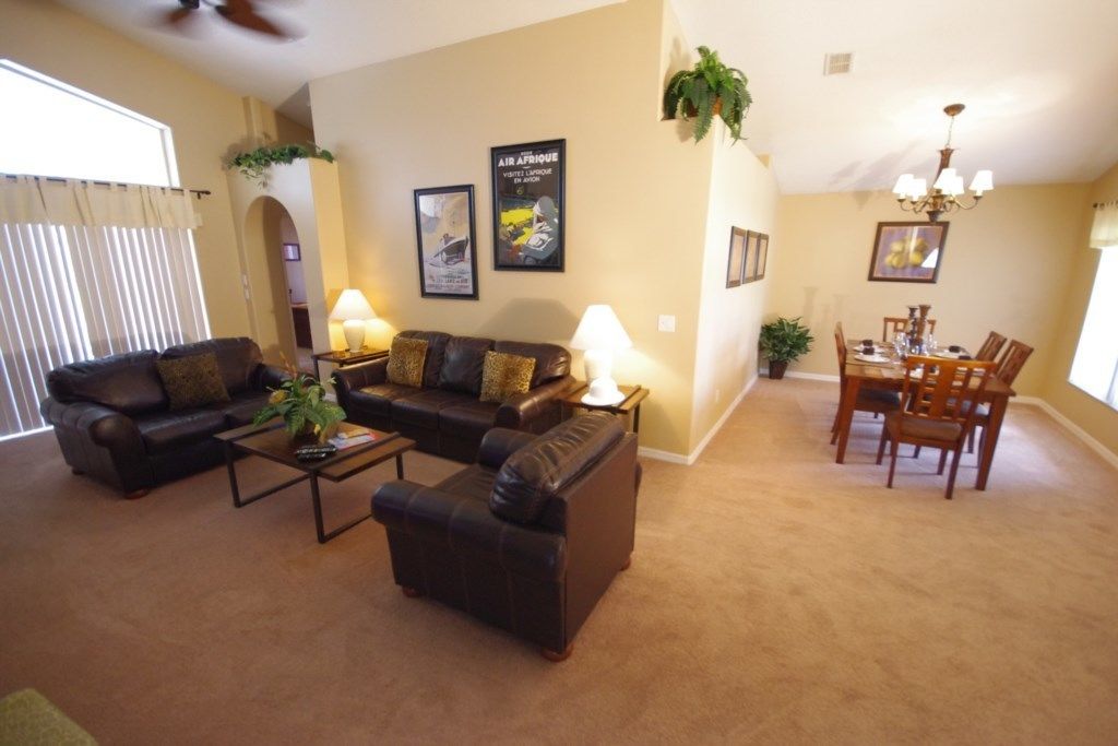 A living room with a sofa set, a coffee table, and a dining area with a table and chairs.