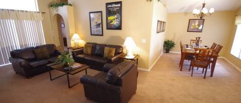 A living room with a sofa set, a coffee table, and a dining area with a table and chairs.