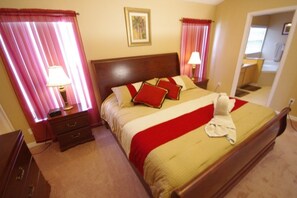 A hotel room with a large bed, two bedside tables, a nightstand, a lamp, and a mirror.
