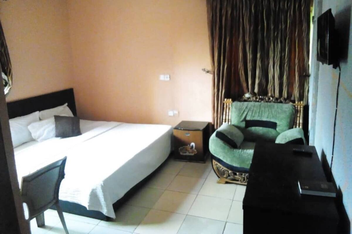 A hotel room with a bed, a chair, a small table, and a television.