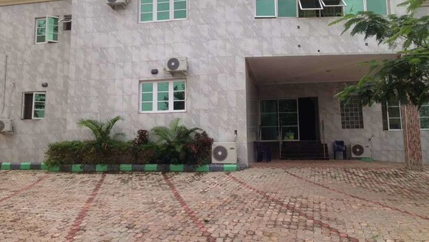 A building with a stone facade, multiple windows, and a paved entrance area. - Ekulu Greens Classic Suites (Enugu)