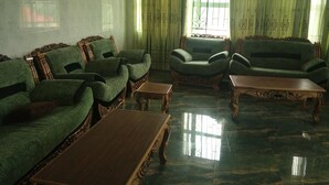 A living room with green patterned sofas, a wooden coffee table, and a patterned rug. - Ekulu Greens Classic Suites (Enugu)