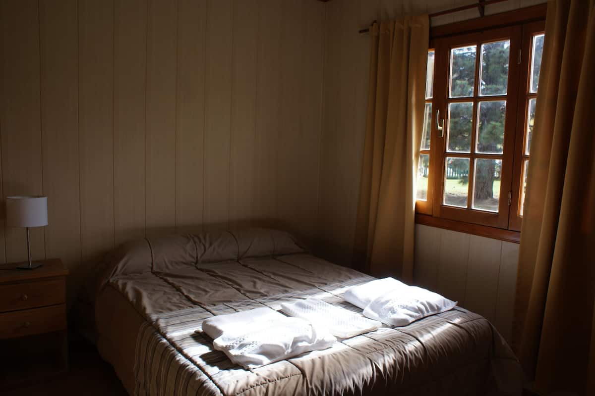 A bedroom with a single bed, a nightstand, and a window with curtains.