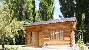 Una cabaña de troncos con fachada de madera, ventanas grandes y una puerta.
