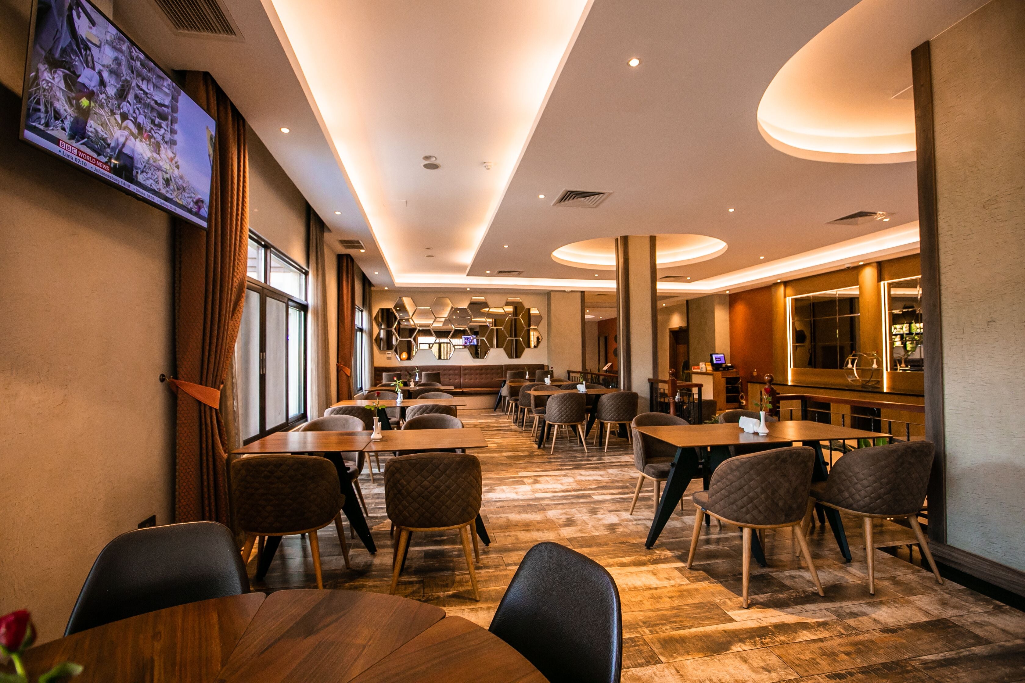 Een hotel lobby met meerdere zithoeken, een bar en een aan de muur bevestigde televisie.