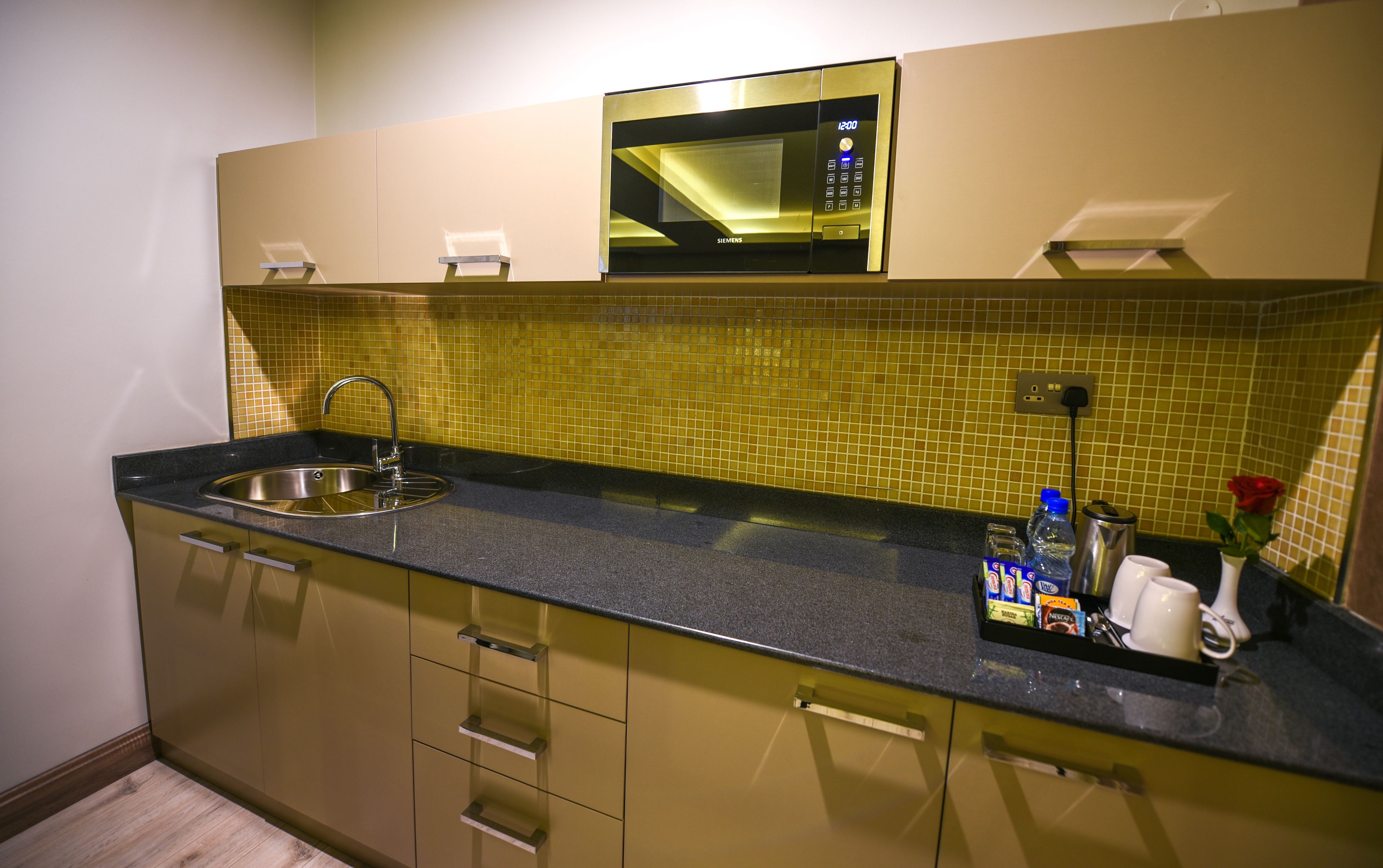 Una cocina moderna con un lavamanos de acero inoxidable, un microondas y un salpicadero de azulejos.