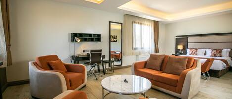 Habitación de hotel con sofá, sillones, una mesita, escritorio, cama y espejo.