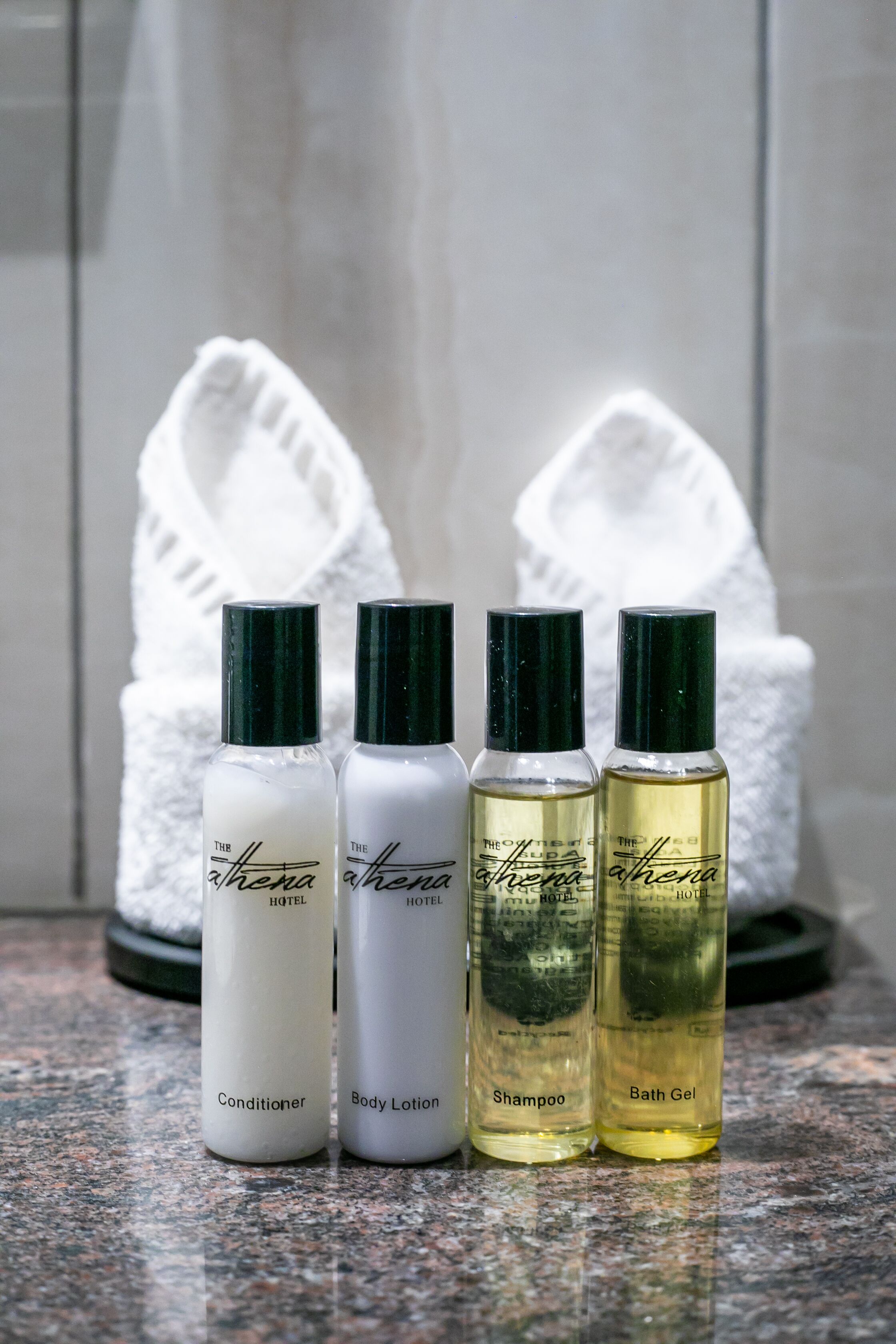 Four bottles of hotel amenities: conditioner, body lotion, shampoo, and bath gel.