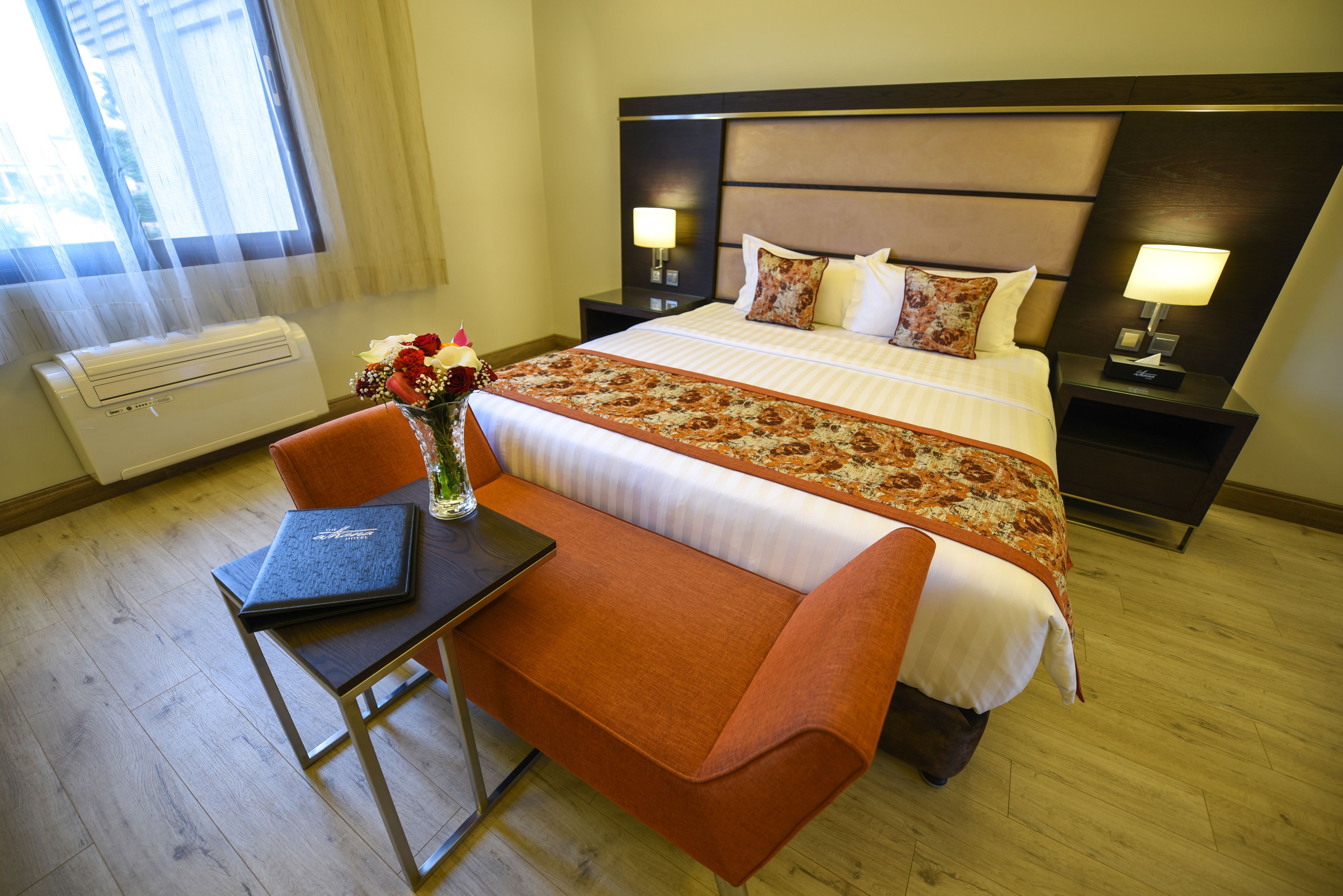 Habitación de hotel con una cama grande, un escritorio, una silla y un jarrón con flores.