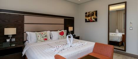 A hotel room with a large bed, a nightstand, a table, and a chair.