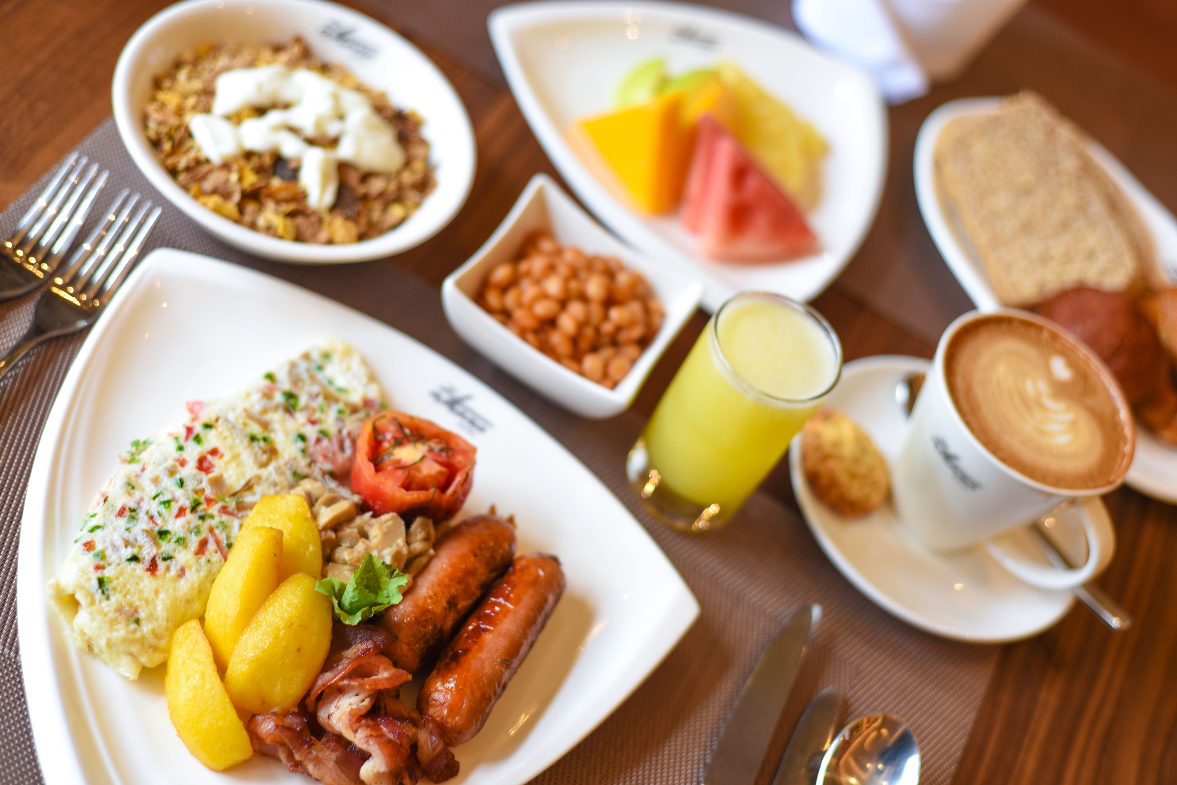 A breakfast setting with plates of food, a glass of juice, and a cup of coffee.