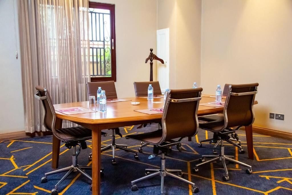 A conference room with a wooden table, six chairs, and water bottles on the table.