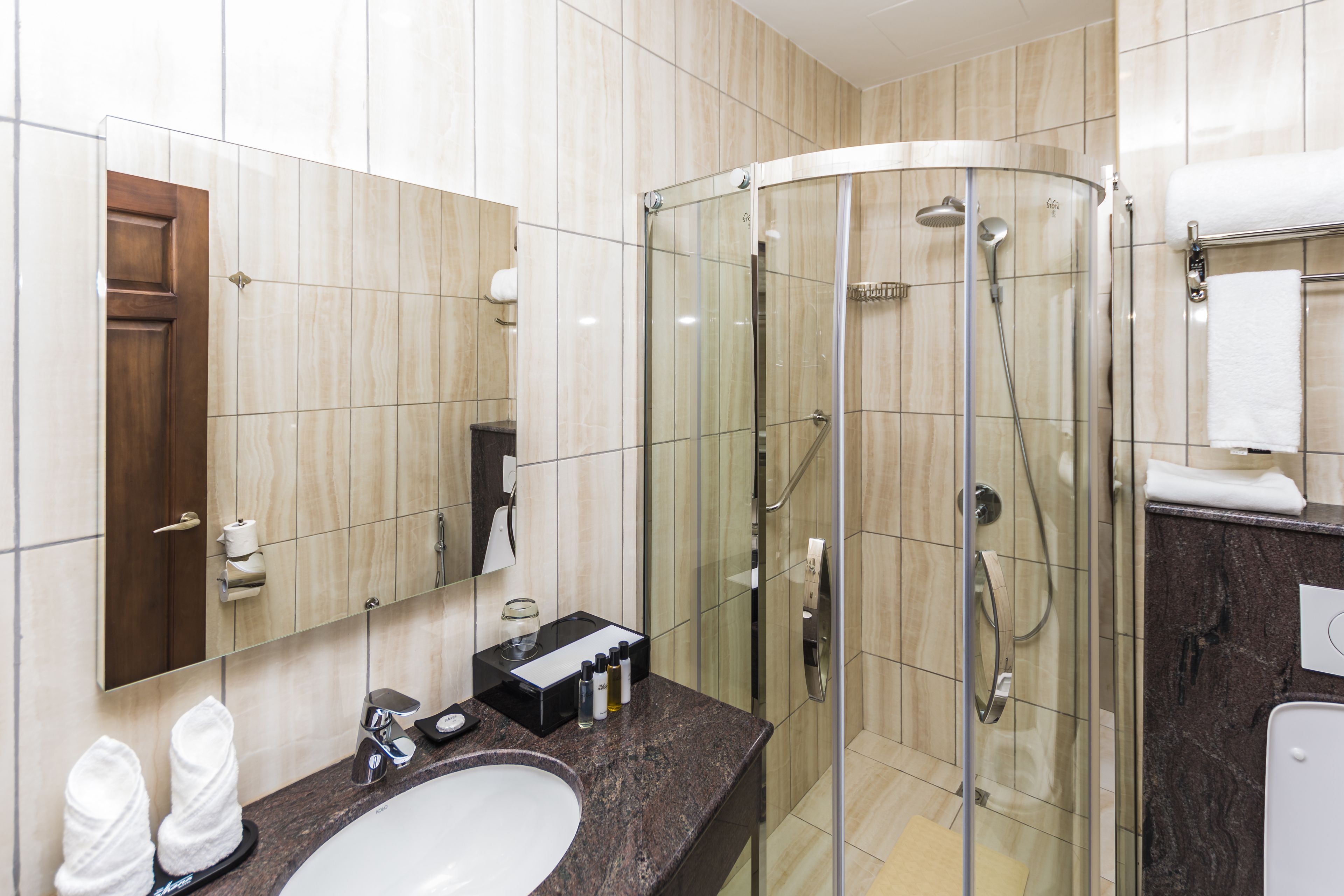 Un baño moderno con ducha de vidrio, lavamanos y espejo.