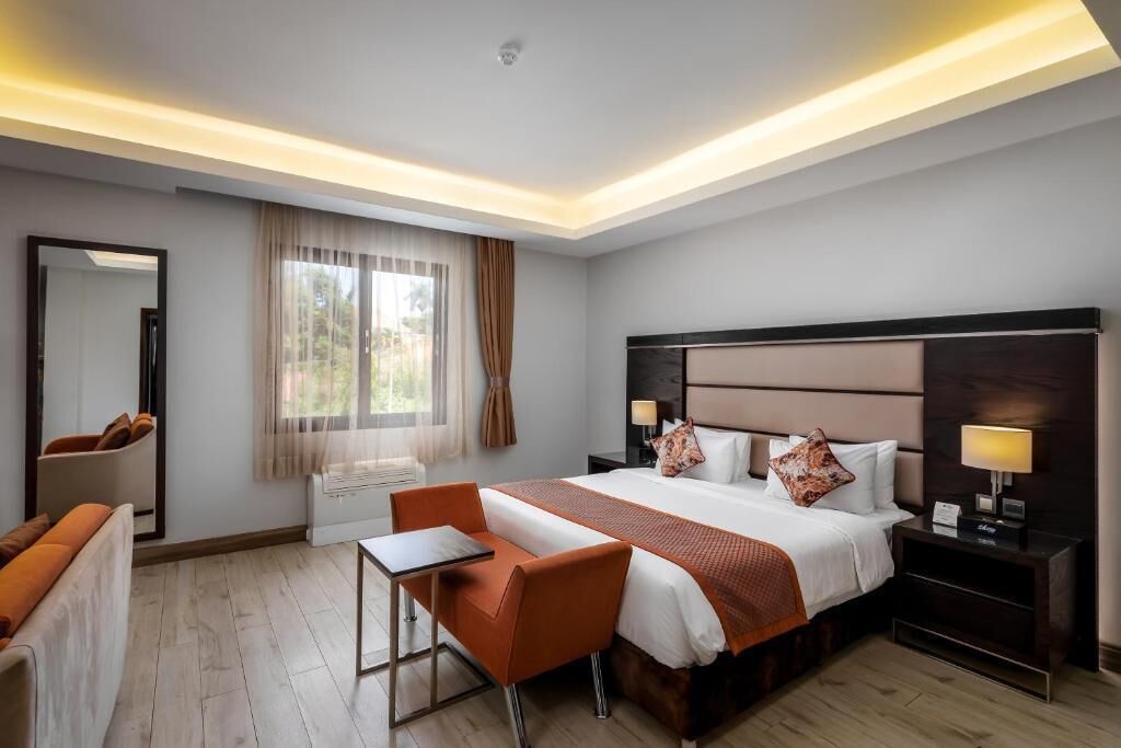 Una habitación de hotel con una cama grande, un escritorio, una silla, una mesita de noche y un espejo.