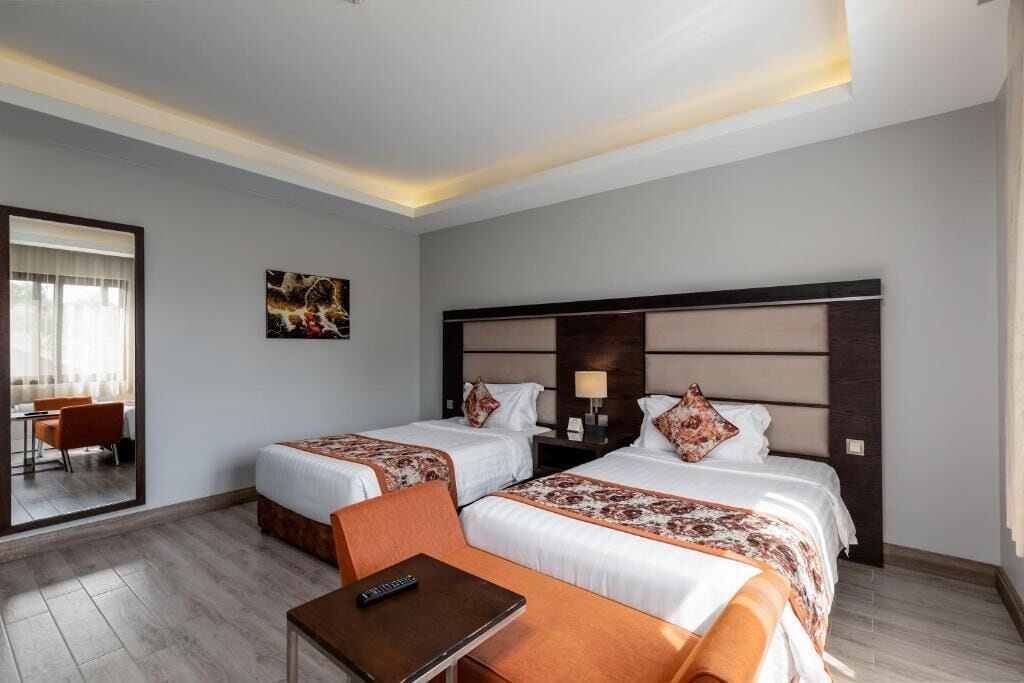 Een hotelkamer met twee bedden, een bureau en een stoel.