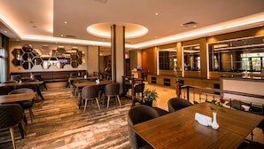 Un restaurant moderne avec des tables et des chaises en bois, un bar et un espace détente avec des bancs rembourrés.