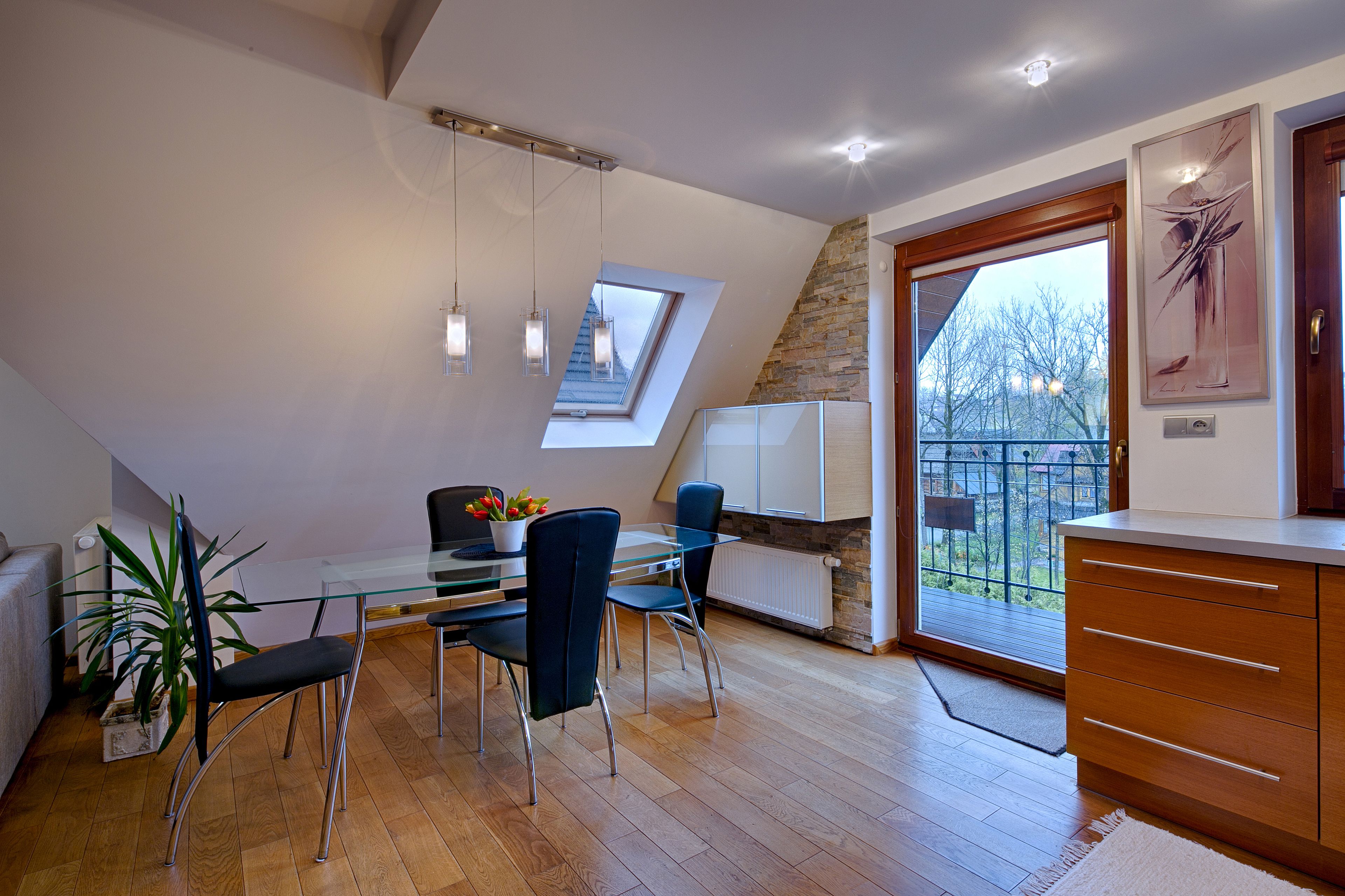 A modern dining area with a glass table, metal chairs, and a potted plant.