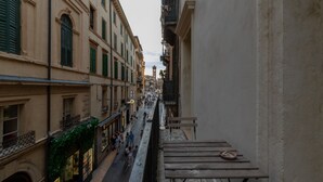 A narrow street with buildings on either side, a bench, and a clock.