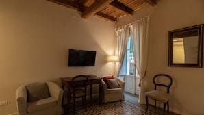 A living room with a sofa, a small table, a TV, and a patterned floor.