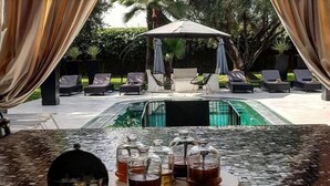 Un coin petit-déjeuner aménagé avec vue sur la piscine, comprenant une table avec des assiettes, des verres et un barbecue.
