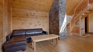 A wooden interior with a stone fireplace, a leather sofa, and a wooden table. - Tatrzańskie Echo Domki Regionalne (Zakopane)