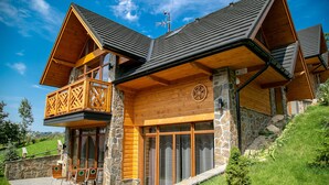 A wooden cabin with a stone foundation, large windows, and a balcony. - Tatrzańskie Echo Domki Regionalne (Zakopane)